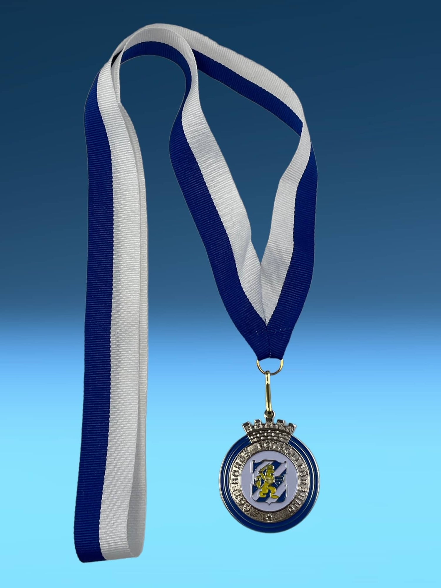Silverfärgad medalj med blå och vit randig band, rund form med dekorativ kant och emblem, fotbollsmedalj.