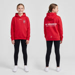 Två tjejer i röd Craft Community 2.0 hoodie med GF Kennedys klubbemblem på bröstet och textloggan GF Kennedy Göteborg på ryggen